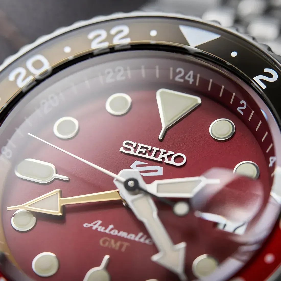 Detail dekat dial maroon sunray dan jarum GMT emas pada Seiko 5 Sports HDB016